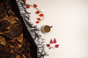 Autumn composition. Cup of coffee, shawl, autumn leaves, physalis on a white background.
