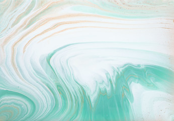 photography of abstract marbleized effect background. turquoise, gold, blue and white creative colors. Beautiful paint.