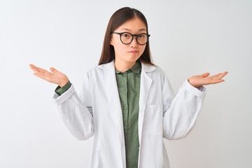 Young chinese scientist woman wearing coat and glasses over isolated white background clueless and...
