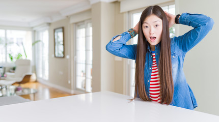 Fototapeta na wymiar Young beautiful asian woman with long hair wearing denim jacket Crazy and scared with hands on head, afraid and surprised of shock with open mouth