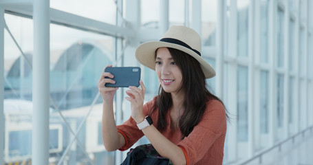 Woman take photo on cellphone in the airport