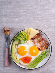 Top view of ketogenic diet breakfast on the white plate with a fork on linen fabric with copy space