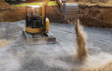 Excavator bucket moving gravel stones for foundation building