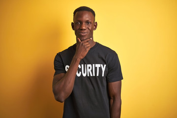 African american safeguard man wearing security uniform over isolated yellow background looking...