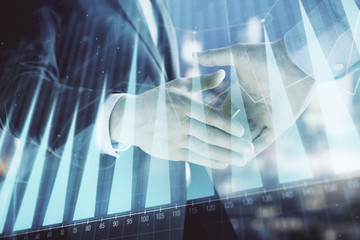 Double exposure of financial chart on cityscape background with two businessmen handshake. Concept of financial analysis and investment opportunities