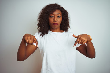 Young african american woman wearing t-shirt standing over isolated white background Pointing down...