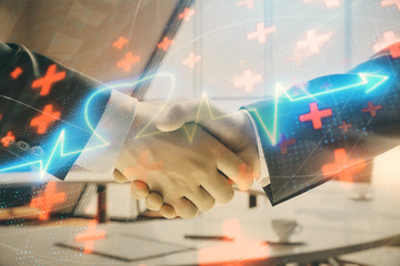 Multi exposure of heart icon hologram on office background with two men handshake. Concept of medical education