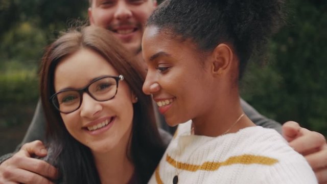 Smiling African Brazilian American young woman posing with her friends and making funny faces in front of camera whilst taking a selfie