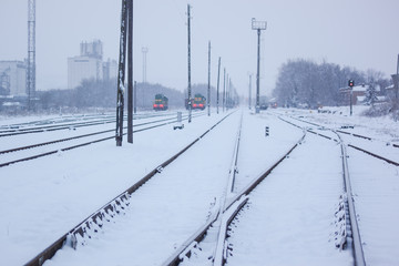 railway tracks go to the railway station where the locomotives stand in the winter on a snowy morning