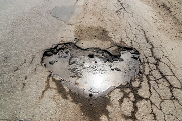 Road asphalt with heart shaped pit on it