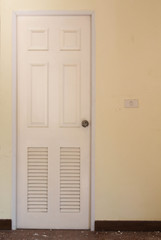 Fototapeta premium White wooden bathroom door with louver on concrete wall.