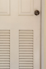 White wooden bathroom door with louver on concrete wall.