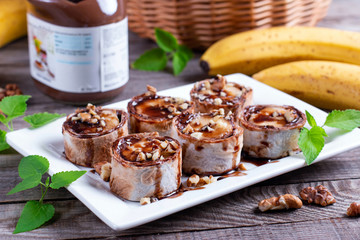 Delicious roll with banana slices on wooden background