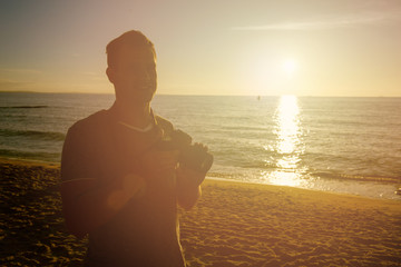 Silhouette of young photographer on the beach