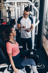 Young fit and attractive woman working out in modern gym together with her personal fitness instructor or coach.