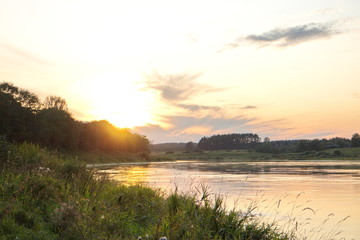 Sunset by the river in the summer countryside