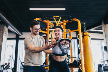 Fototapeta na wymiar Young fit and attractive man and woman exercising workout with kettlebell in modern fitness gym.