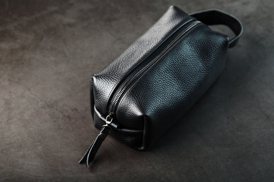 Bag for cosmetics and jewelry made of genuine black leather, on a dark background. Handwork