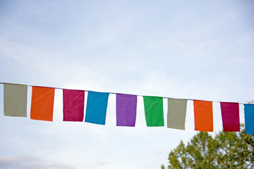 Garland of multi-colored flags on a city street festival. Street decoration for the holiday. Multi-colored pennant, flags on the rope, festive decoration. Flags garland for fun festa party event.