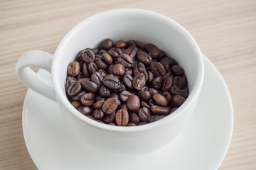 fresh roasted coffee beans in white cup on wood table