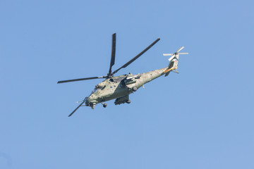 A military light green helicopter flying in the blue sky
