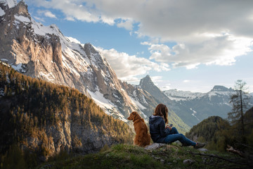 Fototapeta premium girl with a dog in the mountains. Autumn mood. Traveling with a pet. Nova Scotia Duck Tolling Retriever