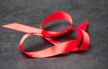 Cinta roja sobre fondo negro, intento de lazo, lazo sin acabar.