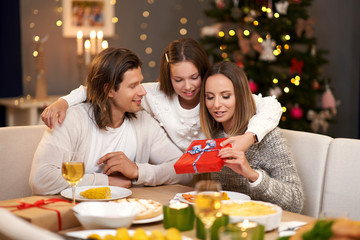 Beautiful family with presents sharing presents during Christmas dinner