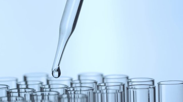 Closeup shot of scientist dripping liquid into test tube