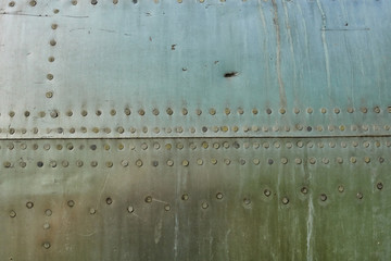Aluminum surface of the aircraft fuselage. Smooth rows of rivets, there are scratches, dirt