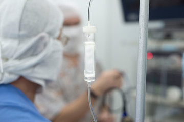 system for intravenous infusion, in focus. Doctors in the background blurring