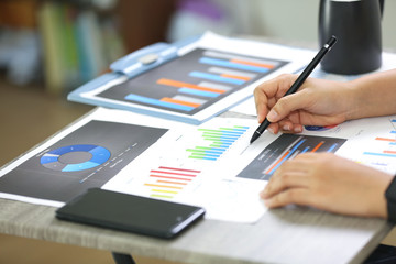 Side View Of Graph Papers On Table and business people writing on paperwork