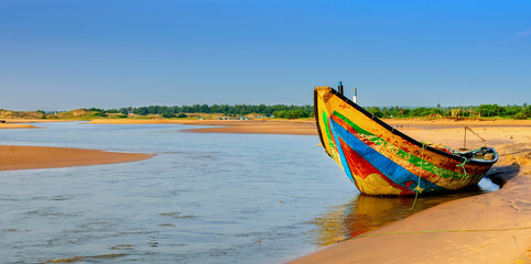 Traditional colorful fishing boat anchored at the confluence of Mahendra Tanaya river and Bay of Bengal