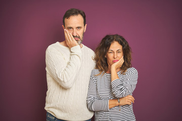 Naklejka premium Beautiful middle age couple wearing winter sweater over isolated purple background thinking looking tired and bored with depression problems with crossed arms.