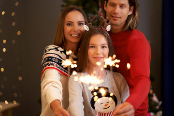 Beautiful family celebrating Christmas and holding sparklers
