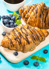 Croissant with fresh berries on blue.