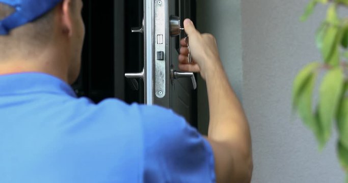 locksmith in blue uniform installing new house door lock