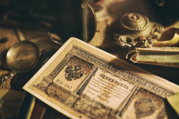 Different antique items on the table: bronze jewelry, banknotes and coins of the Russian Empire, glasses in a case, silverware. Vintage background from collection of antiques. Close-up selected focus