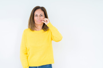 Beautiful middle age woman wearing yellow sweater over isolated background mouth and lips shut as zip with fingers. Secret and silent, taboo talking