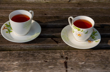 Two cups of tea stand on a wooden surface