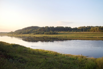 by the river in the countryside on a summer evening