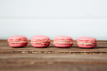 Sweet colorful French macaroon cookies dessert on brown wooden table over white wooden background