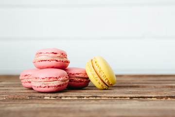 Sweet colorful French macaroon cookies dessert on brown wooden table over white wooden background