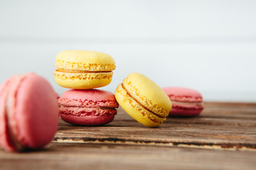 Sweet colorful French macaroon cookies dessert on brown wooden table over white wooden background