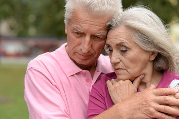 Unhappy senior couple posing in the park