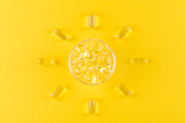 golden omega capsules like sun on yellow background, flat lay