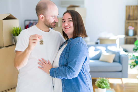Young couple smiling very happy showing keys of new home, moving and buying new apartmet concept