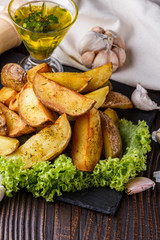 Potato wedges baked in their skins with lettuce on wooden background.