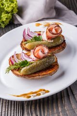 Halves baked potato with pickled cucumber, dill, salo and onion on wooden table