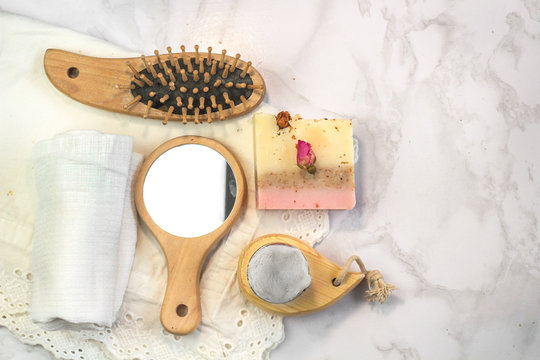 handmade multicolored soap with herbs and rosebuds, comb, towel, mirror, face brush on a marble background with. Spa set kit for face and body treatments flat lay istagram  style